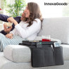 Mujer sonriendo en el sofá mientras usa una tablet junto a la bandeja reposabrazos InnovaGoods